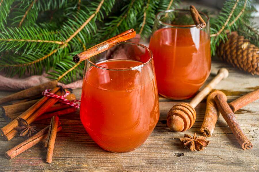 two glasses sit in front of pine trees with red tea mocktails inside