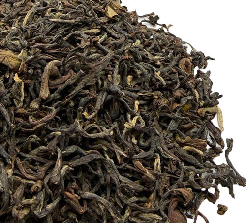 Close-up of dried black darjeeling tea leaves on a white background