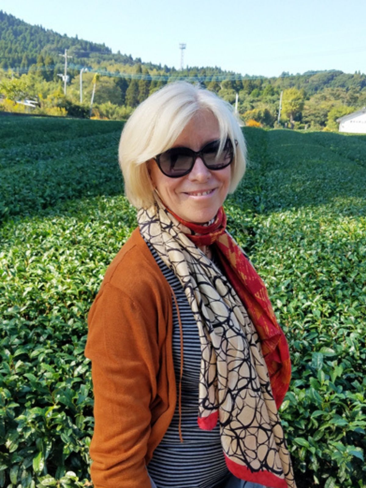 Maria stands in front of a green tea plantation sourcing premium green tea in Japan. 