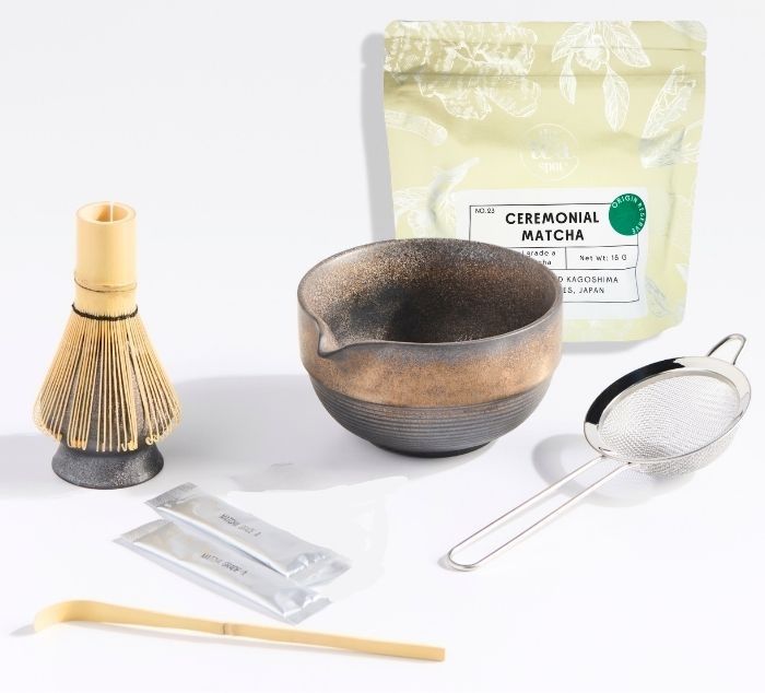 Matcha set with bowl, bamboo whisk, and matcha package on a white background