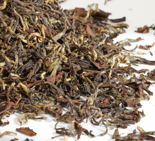 A close-up pile of loose-leaf darjeeling tea leaves on a plain white background. 