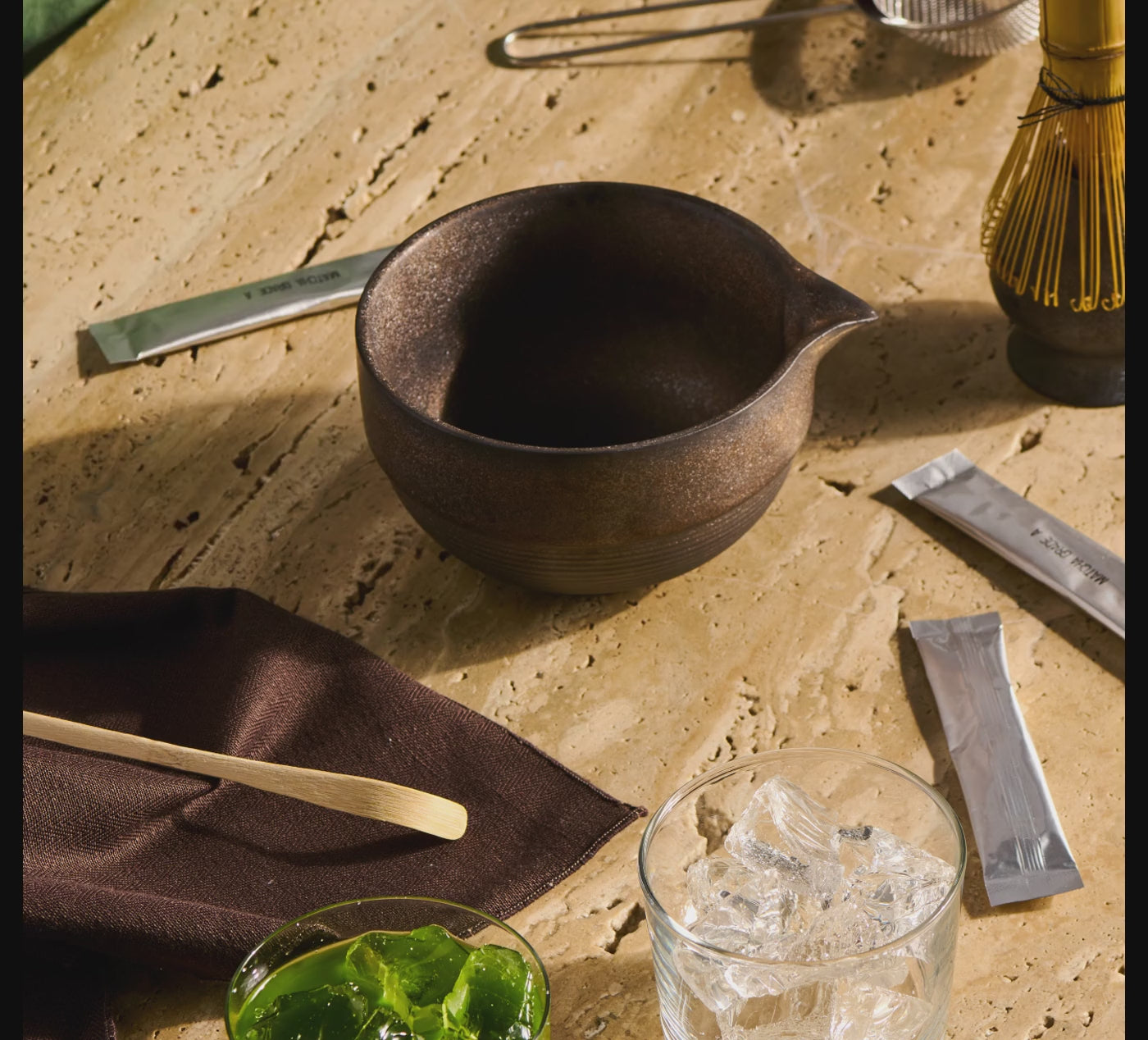 a person whisks matcha in a bowl and pours it into a glass
