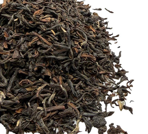 Close-up of dried black darjeeling tea leaves on a white background