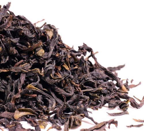 Close-up of dried ya shi xiang tea leaves on a white background